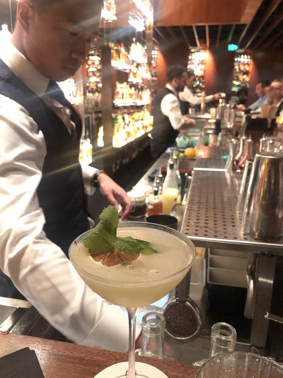A bartender garnishing a cocktail behind the bar at Grain Bar